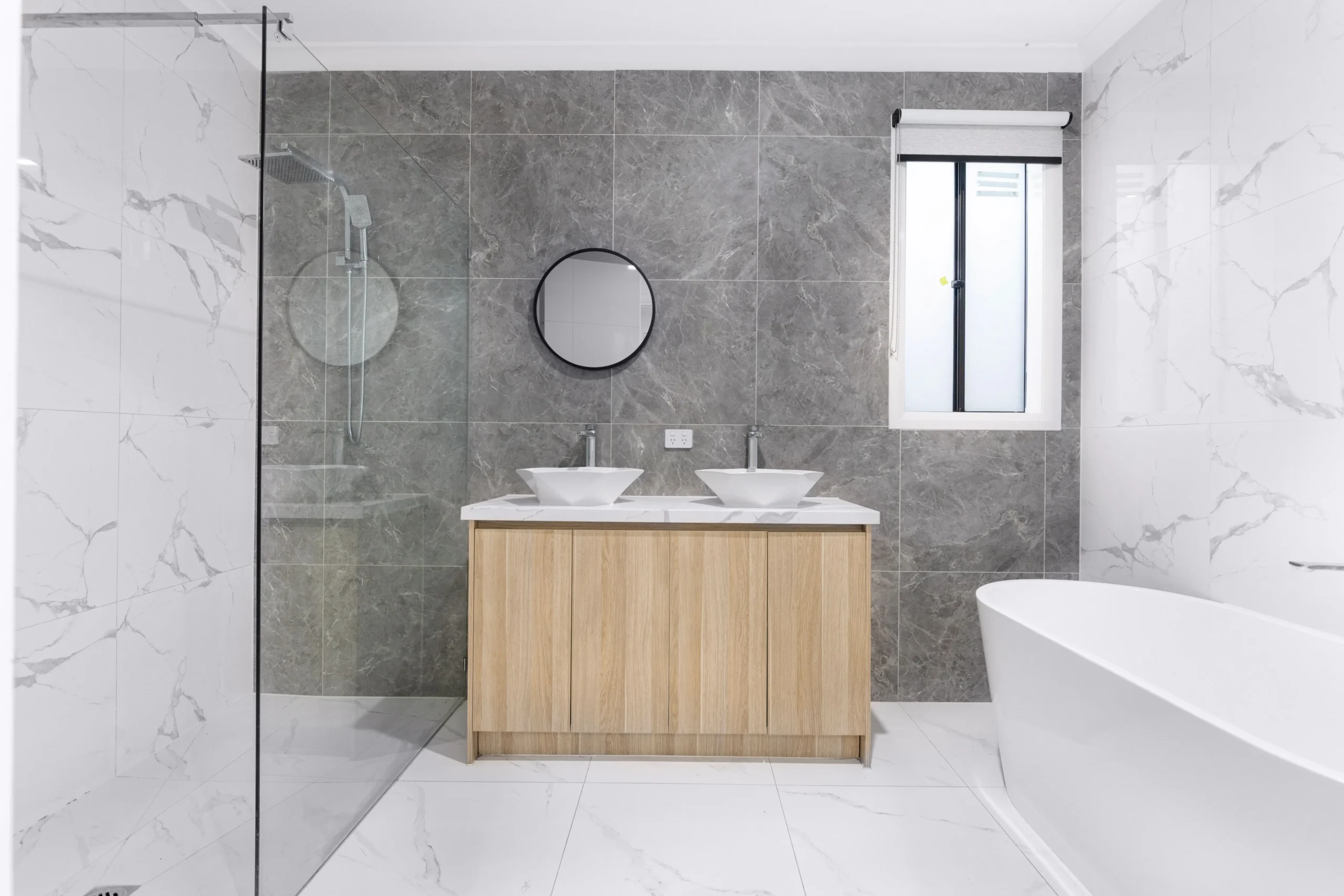 Modern renovated bathroom in Australia featuring a timber bathroom vanity, frameless shower, and floor-to-ceiling tiling illustrating bathroom remodelling costs.