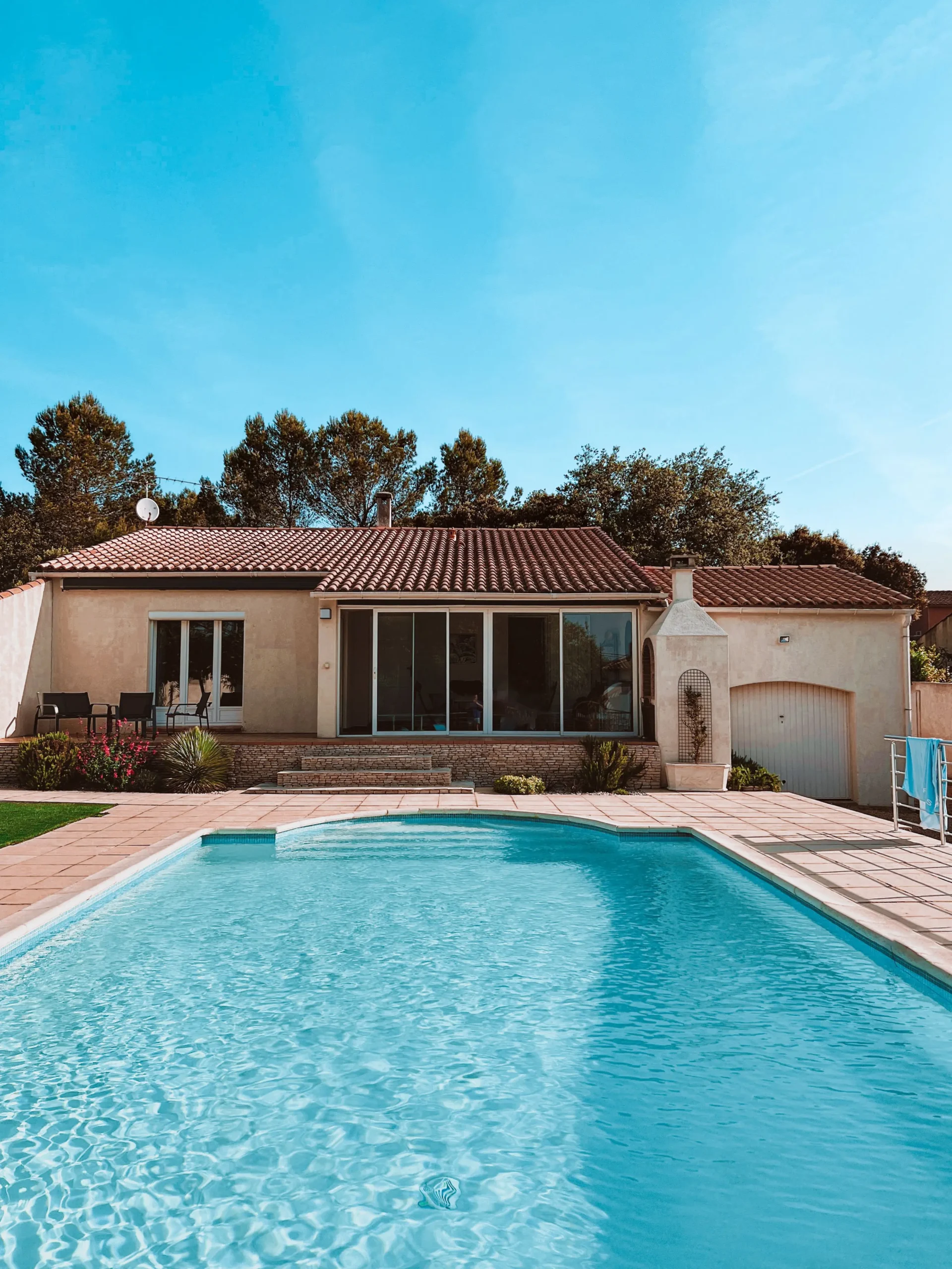 Modern backyard concrete inground swimming pool with timber decking and architectural water feature illustrating premium swimming pool builders prices in Australia